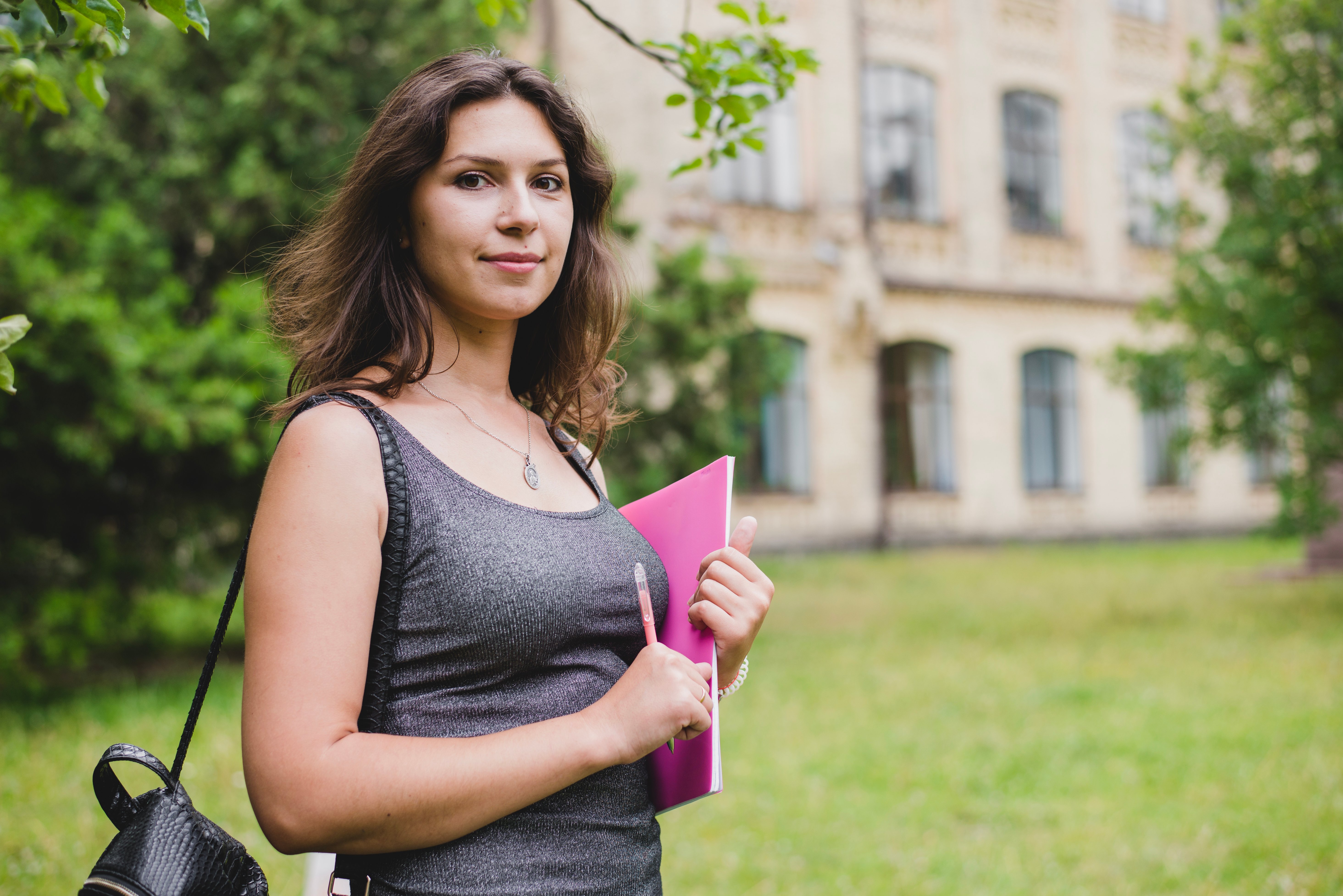 girl-standing-holding-notebook-pencil-smiling