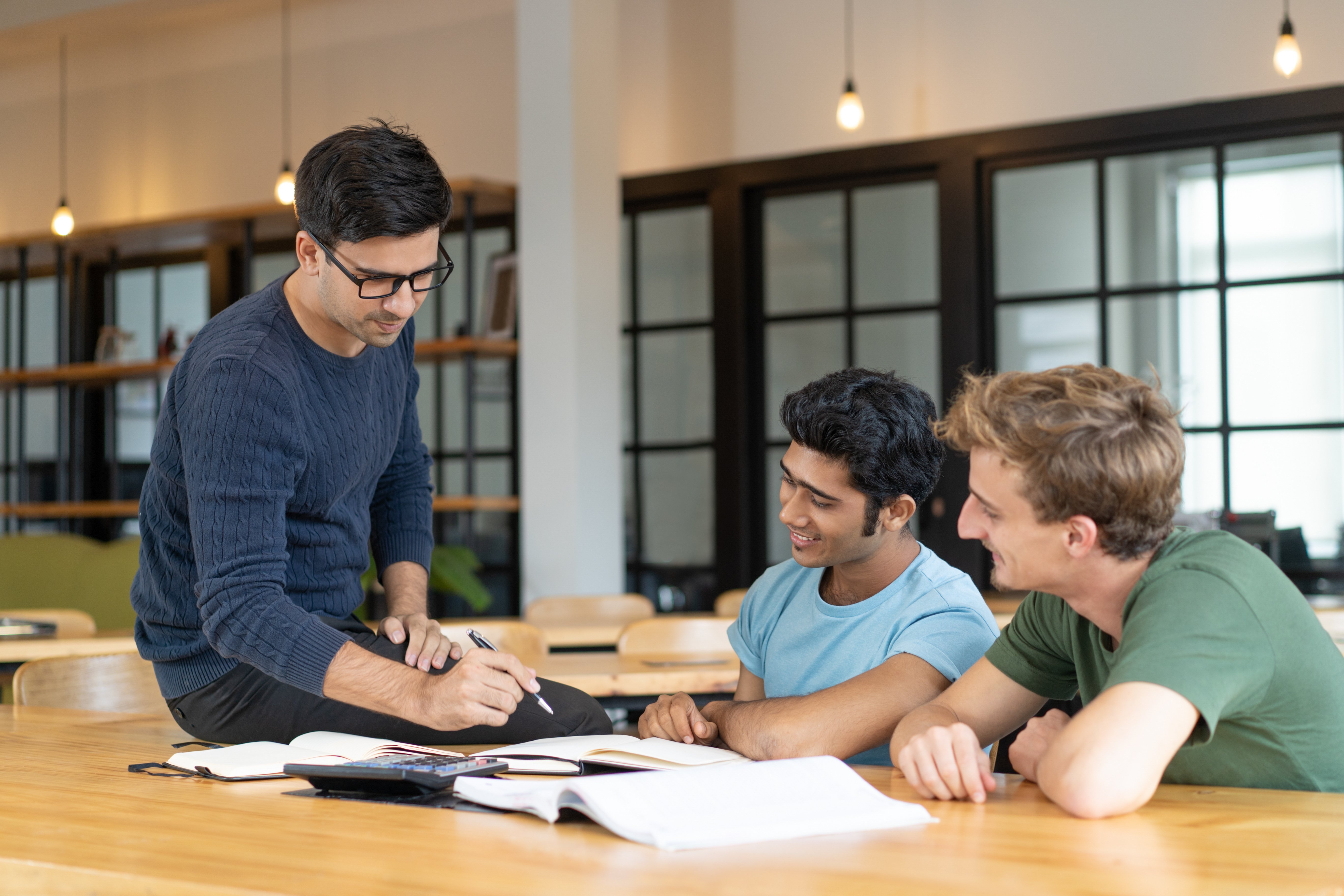 serious-teacher-checking-assignment-two-students (1)